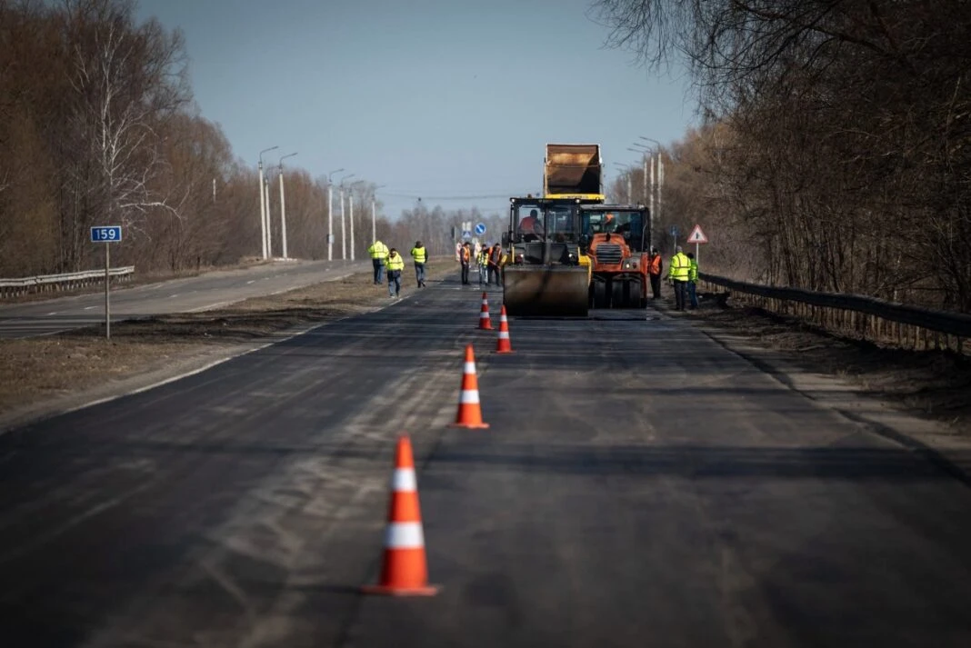 Дорожня техніка та робітники асфальтують трасу на Житомирщині, рух обмежено конусами