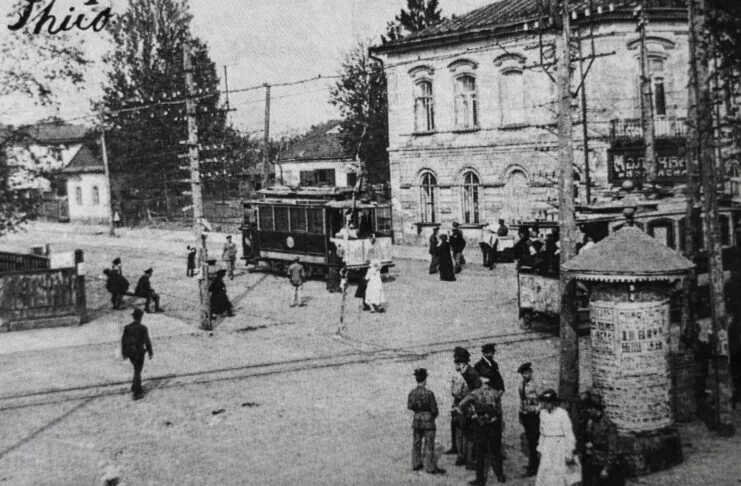Старий трамвай на вулицях Житомира початку XX століття серед двоповерхових будівель та перехожих