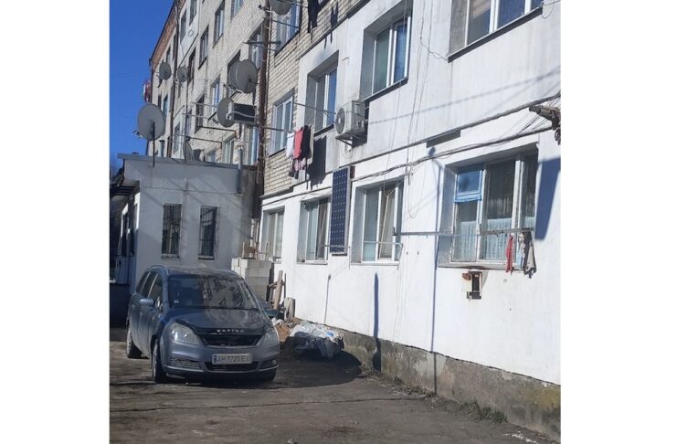 Багатоповерховий будинок на вулиці Грушевського у Житомирі з припаркованим авто
