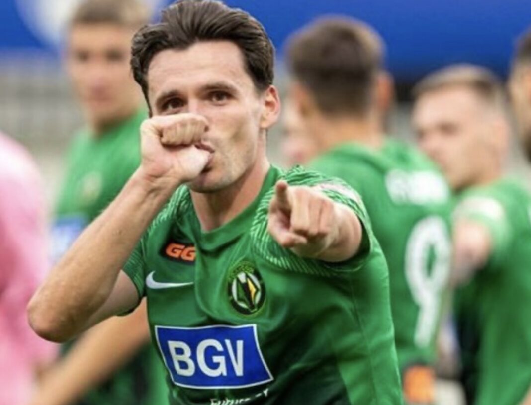 Гравець житомирського футбольного клубу «Полісся» у зеленій формі емоційно святкує гол, вказуючи пальцем у камеру