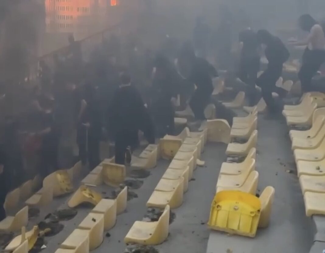Гостьовий сектор Центрального стадіону у Житомирі, затягнутий димом від фаєрів, зі зламаними пластиковими сидіннями