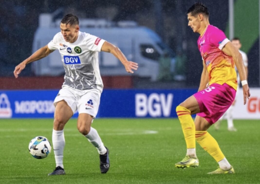 Гравець житомирського «Полісся» у білій формі контролює м'яч під час матчу з гравцем команди-суперника у рожево-жовтій формі