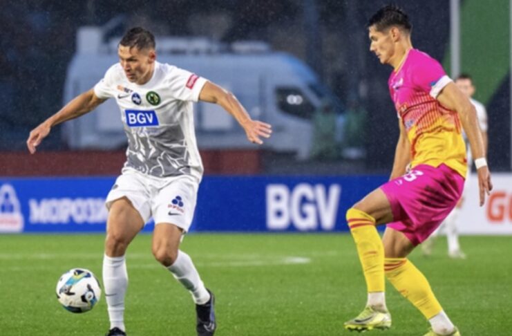 Гравець житомирського «Полісся» у білій формі контролює м'яч під час матчу з гравцем команди-суперника у рожево-жовтій формі