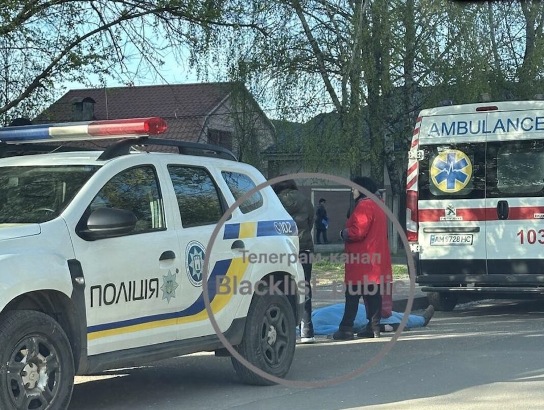 Поліцейський автомобіль Renault та карета швидкої допомоги Peugeot припарковані біля накритого блакитною тканиною тіла людини на вулиці