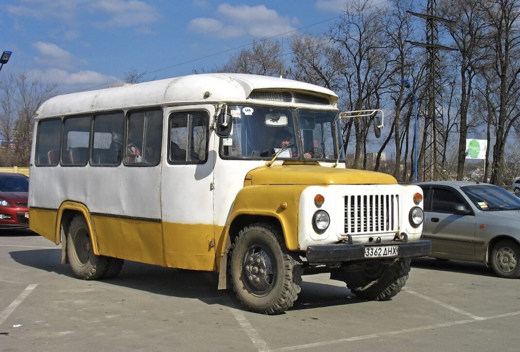 Старий пасажирський автобус моделі ПАЗ біло-жовтого кольору припаркований на асфальті поруч з іншими автомобілями