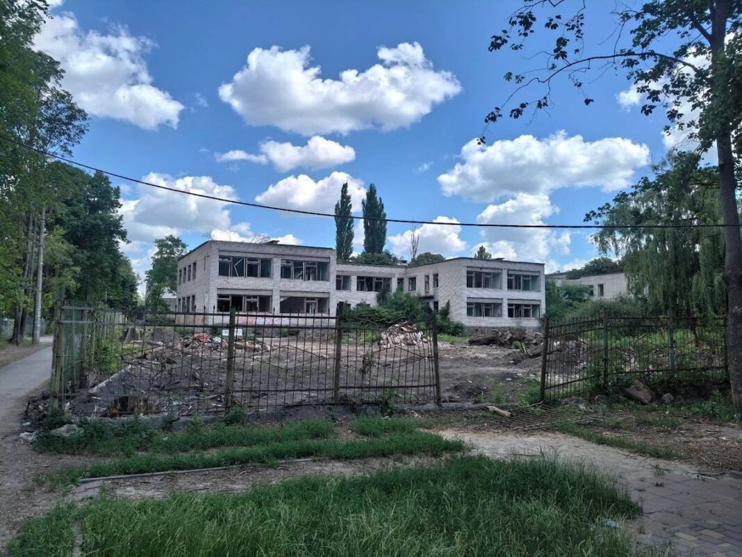 Занедбана двоповерхова цегляна будівля колишнього дитячого садка та Інституту підприємництва за іржавим металевим парканом у Житомирі